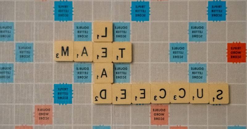 Scrabble tiles on gameboard with Leader, Team, and Success showing